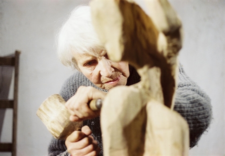 Louise Stomps bearbeitet eine Figur aus Holz in ihrer Werkstatt in der Kumpfmühle bei Rechtmehring, 1987, Foto: Amrei-Marie