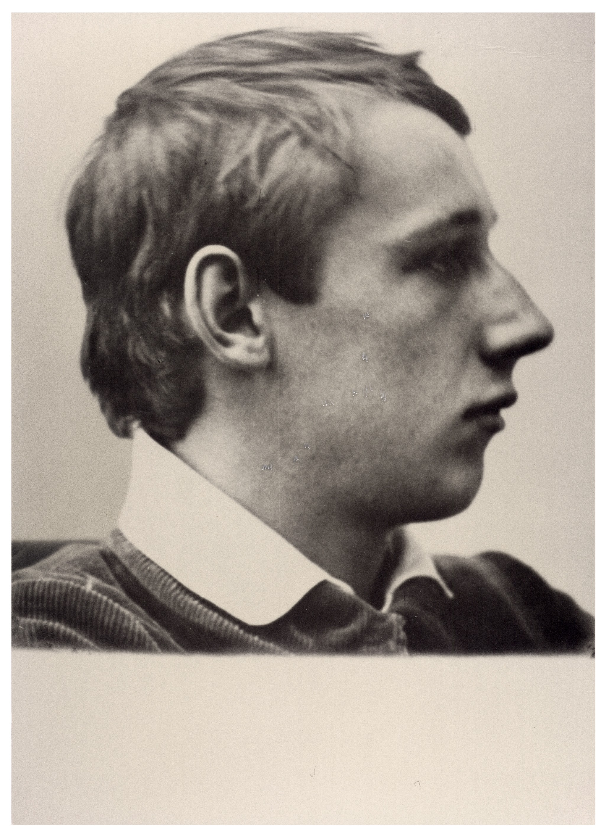 Die Schwarz-Weiß-Fotografie von 1913 zeigt das Profil von Peter Kollwitz (1896–1914), der nach rechts blickt. Er trägt ein dunkles, geripptes Oberteil mit einem hellen Polokragen und hat kurzes, leicht gewelltes Haar.
