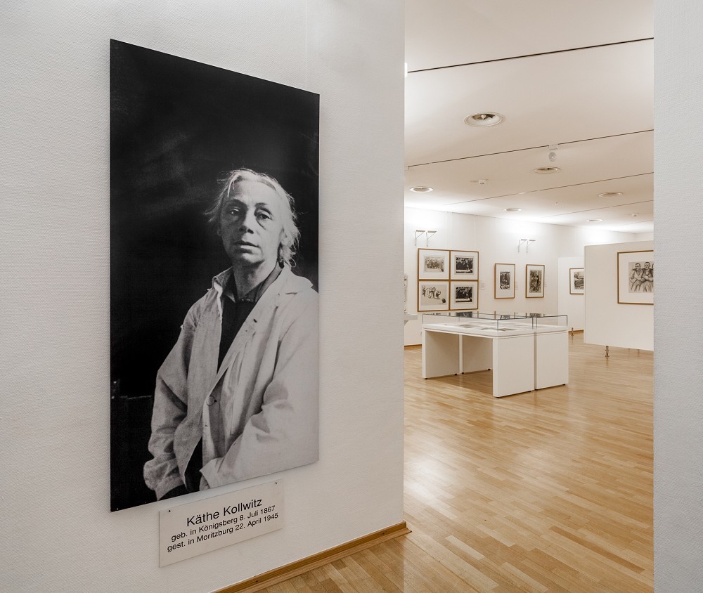 The colour photograph shows a view of the 2015 collection presentation: in the foreground is a photograph of Käthe Kollwitz in her studio. 