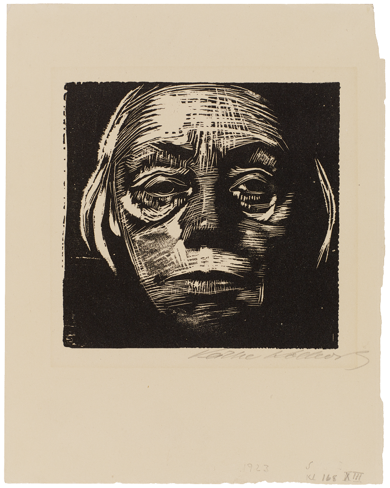 Käthe Kollwitz,  Selbstbildnis von vorn, 1922/23, Holzschnitt, 151 x 156 mm, Kn 193 XIV b 

Das Foto zeigt das Käthe Kollwitz' Selbstbildnis von 1922/23: ein frontales Gesicht, das als kontrastreicher Holzschnitt mit groben, weißen Linien aus einem tiefschwarzen Hintergrund hervortritt. Die Züge wirken durch die tiefen Schatten in den Augenhöhlen und die markanten Furchen auf der Stirn sowie an den Wangen sehr ernst, müde und von Lebenserfahrung gezeichnet. Kurze, helle Haarsträhnen rahmen das schattige Gesicht ein, wobei der durchdringende Blick die Betrachter:innen direkt fixiert.