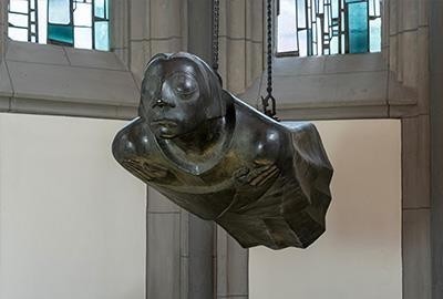 Die Aufnahme des Fotografen Chris Franken zeigt die Bronzeplastik »Der Schwebende« von Ernst Barlach, den Zweitguss nach dem Original-Werkmodell von 1939 an seinem heutigen Ort in der Kölner Antoniterkirche, frontal nach links gewandt. Die lebensgroße, waagerecht schwebende Bronzefigur hängt an zwei Ketten frei in der Luft, wobei ihr gerader Körper und die vor der Brust gekreuzten Arme eine tiefe Ruhe ausstrahlen. Das Gesicht der Skulptur hat geschlossene Augen und wirkt wie insich versunken, während die fließende Form des Gewandes den Eindruck eines sanften Fluges verstärkt.